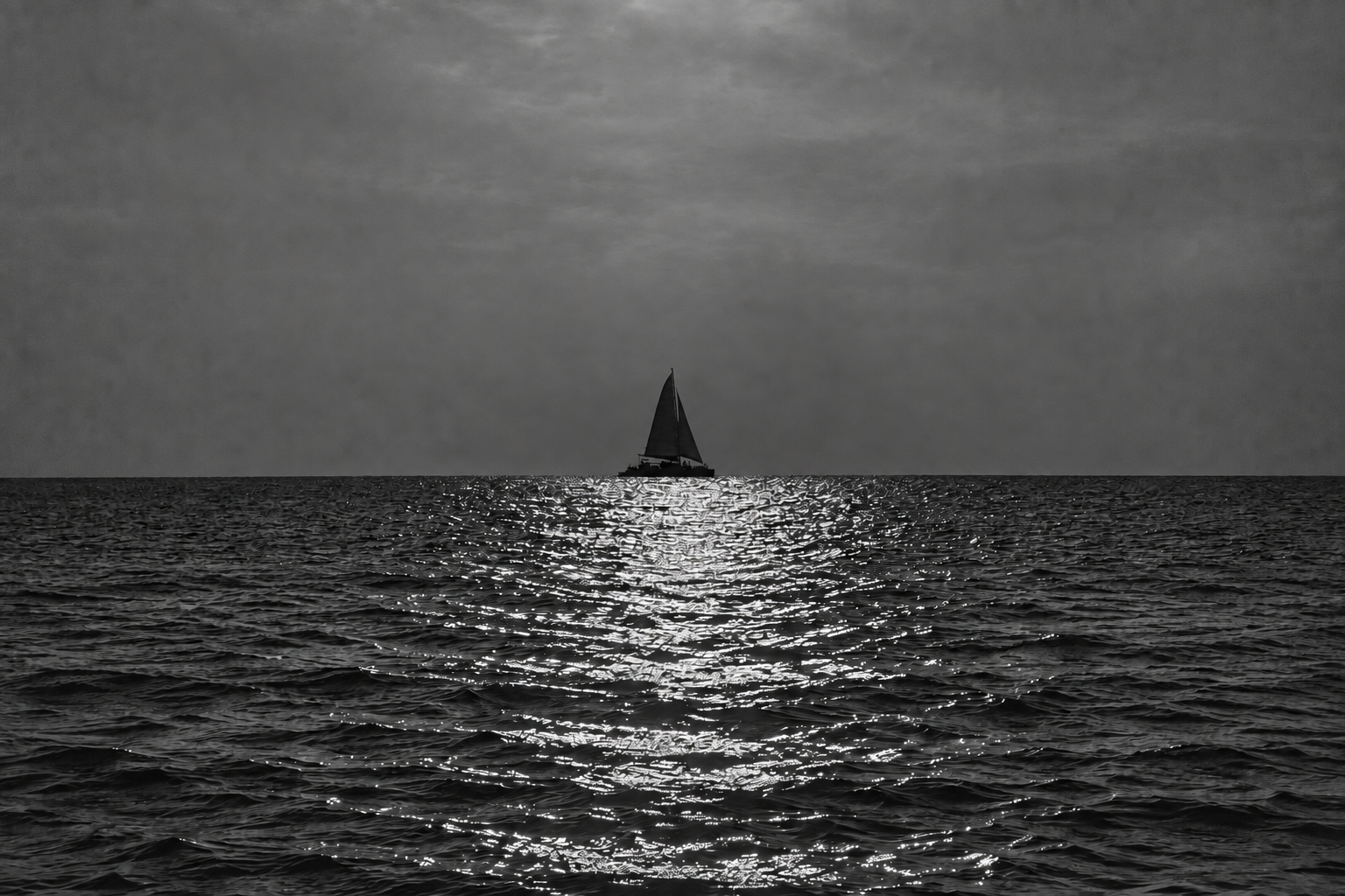 A solitary sailboat on a shimmering monochrome sea